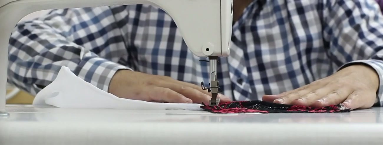 Worker sewing garment panels on an industrial machine